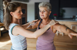 An older woman stretches and smiles with a gym trainer after urinary incontinence treatment in Ocala.