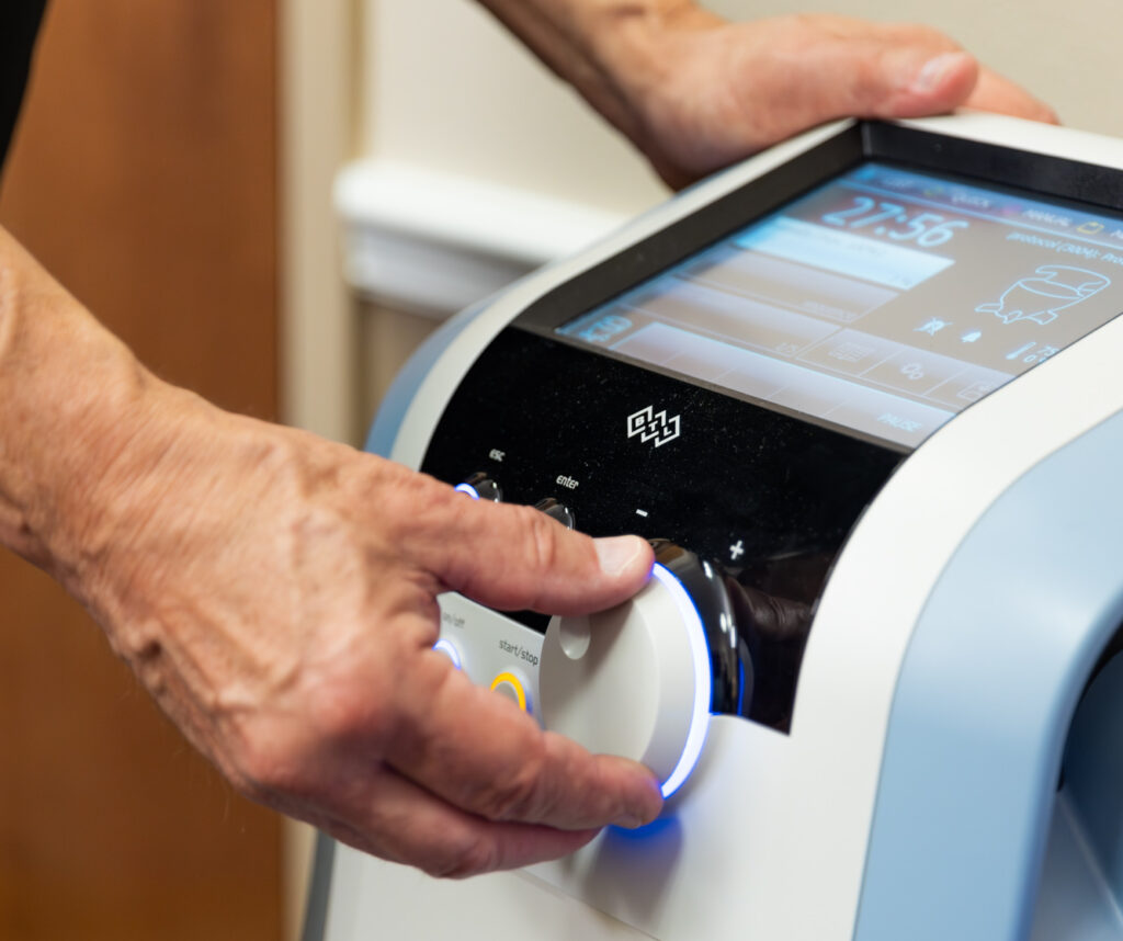 A provider's hand turns on the Emsella, a urinary incontinence treatment near The Villages, FL.
