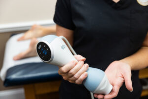 A provider holds the applicator for Emtone, a device for body contouring in Ocala