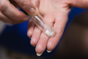 A close-up of a provider's hand holding a glass vial of pellets for HRT for women in Ocala.