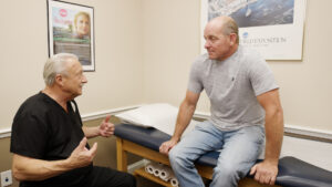A provider talks with a patient sitting on an exam table about the benefits of urinary incontinence treatment near The Villages, FL.
